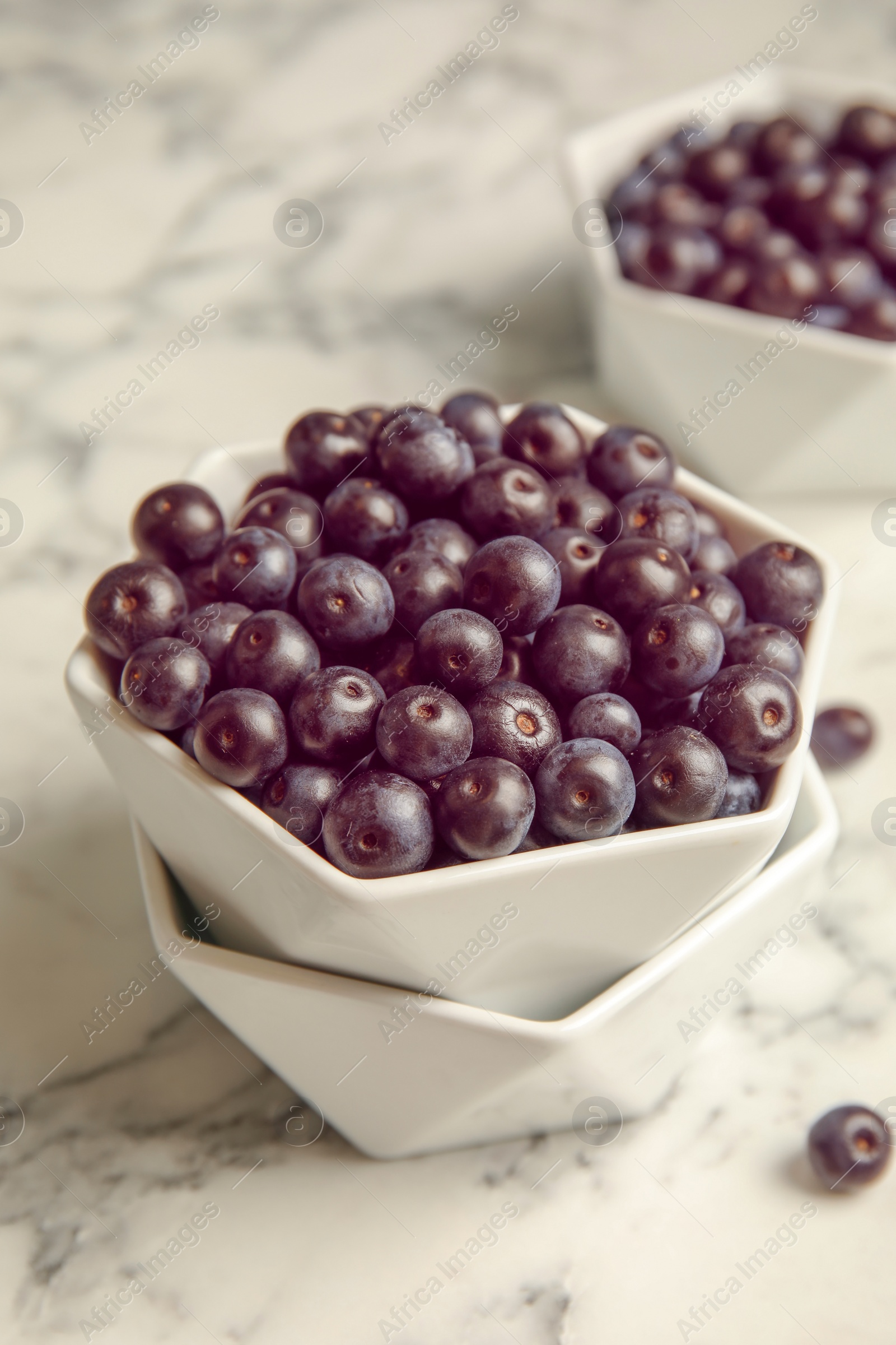 Photo of Bowls with fresh acai berries on table, closeup