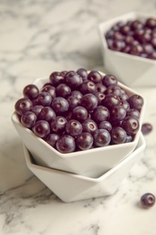 Photo of Bowls with fresh acai berries on table, closeup