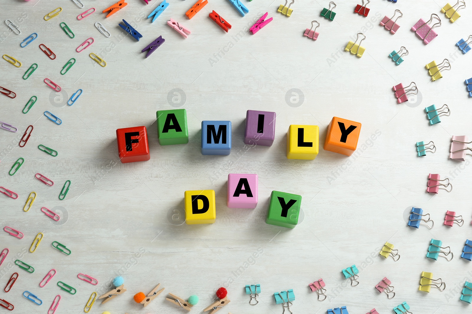 Photo of International Family day. Flat lay composition with cubes, binder clips and clothespins on white wooden background