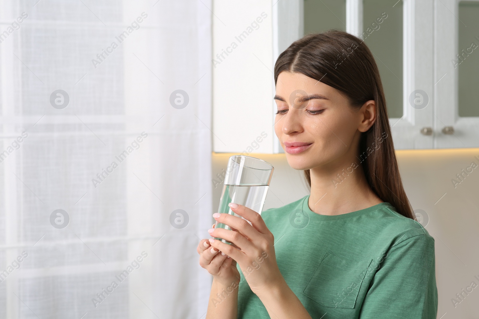 Photo of Healthy habit. Woman holding glass with fresh water indoors. Space for text