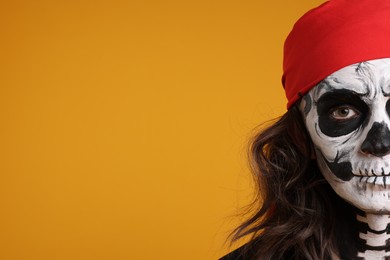 Photo of Man with skull makeup and red bandana on orange background, closeup and space for text. Halloween celebration