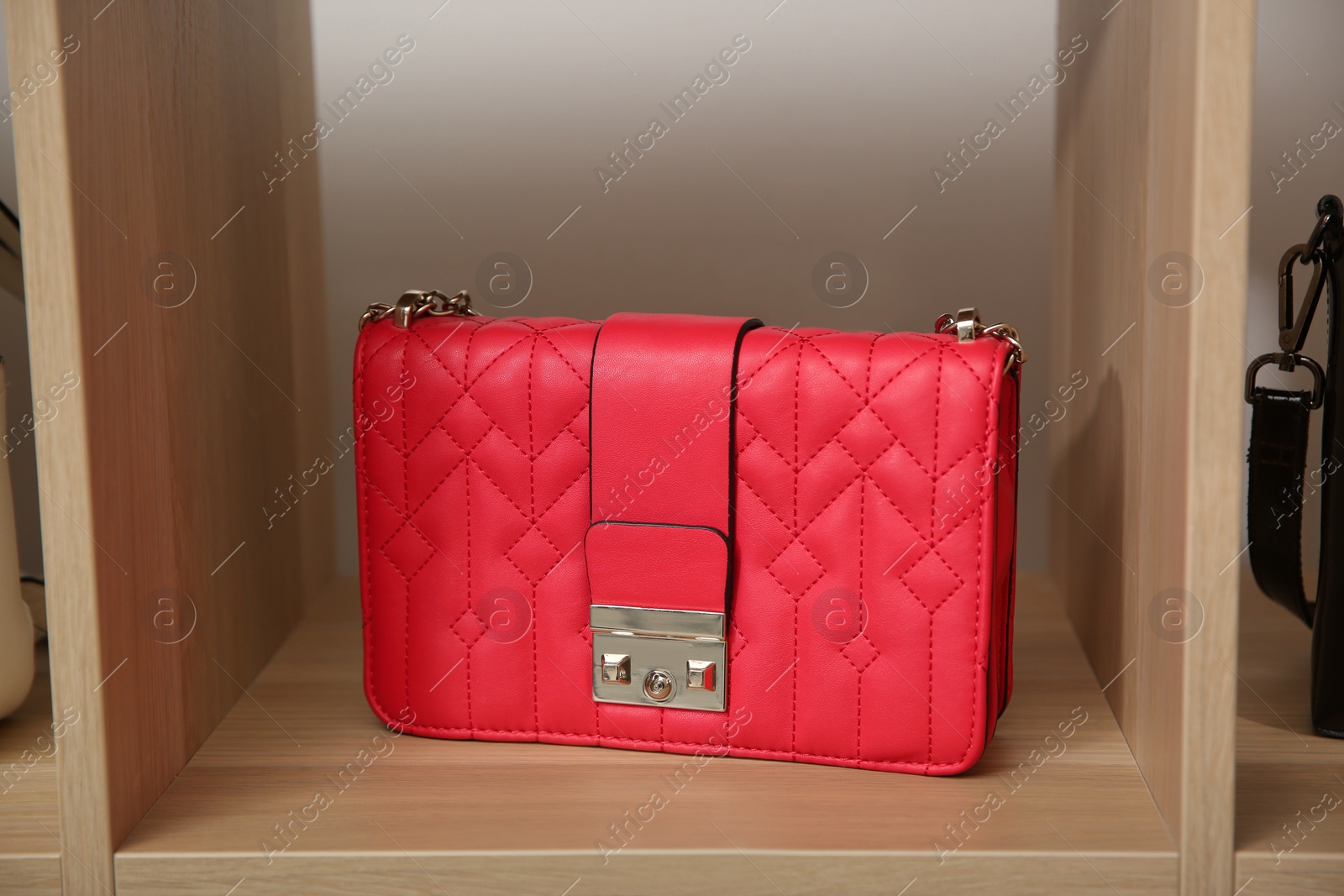 Photo of Stylish red woman's bag on wooden shelf