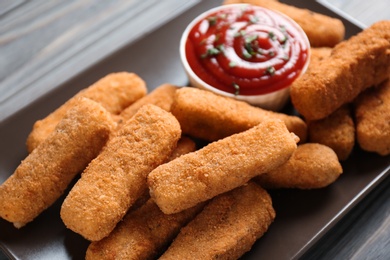 Plate of tasty crispy cheese sticks with sauce, closeup