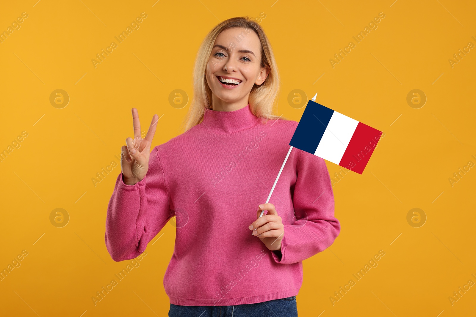 Image of Happy young woman with flag of France showing V-sign on yellow background