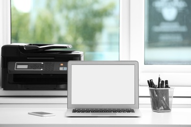 Photo of Modern laptop on desk in room. Home workplace