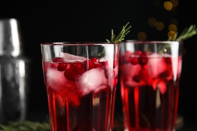 Tasty refreshing cranberry cocktail with rosemary against blurred lights, closeup