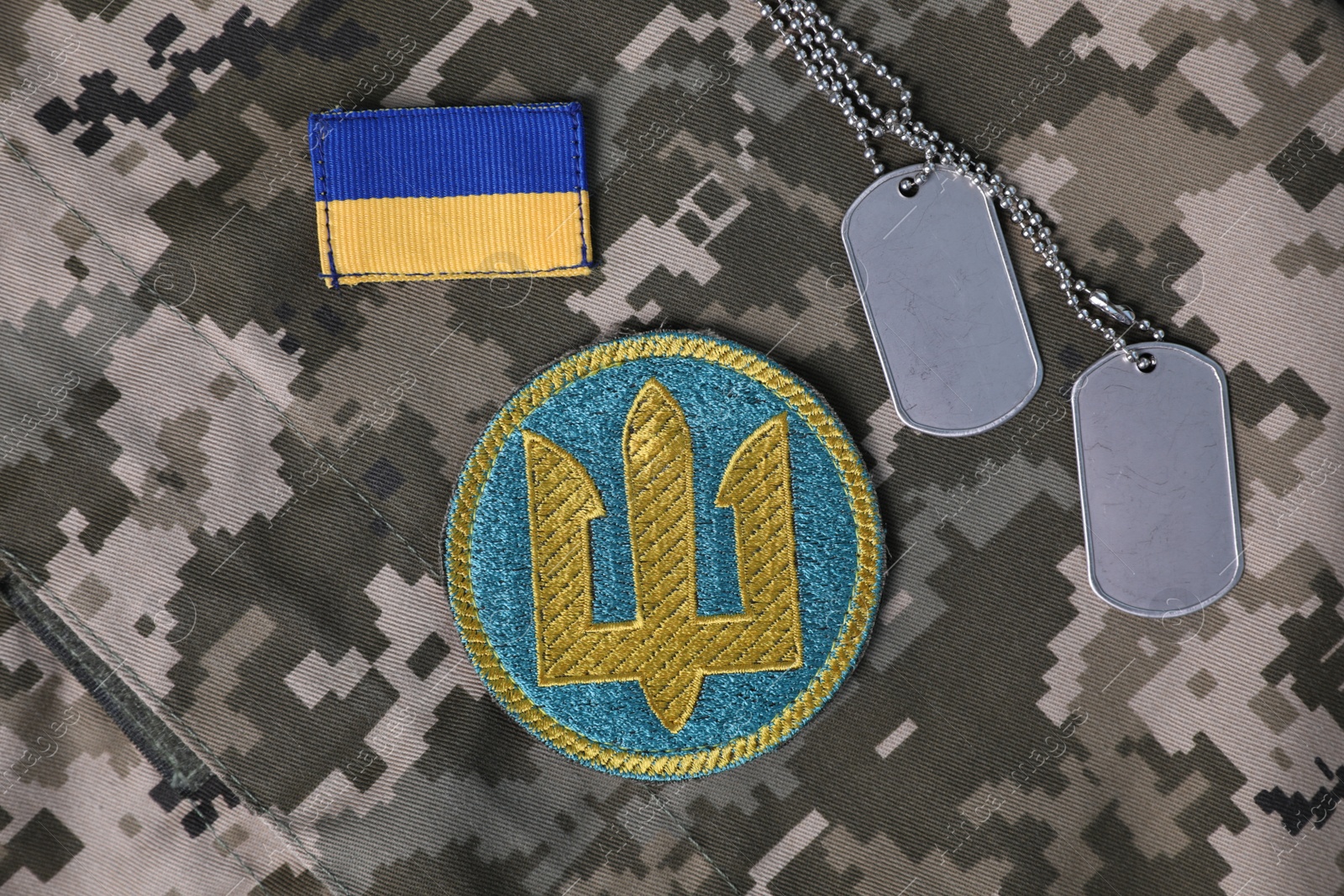 Photo of MYKOLAIV, UKRAINE - SEPTEMBER 19, 2020: Flat lay composition with Ukraine military patches and dog tags on camouflage background