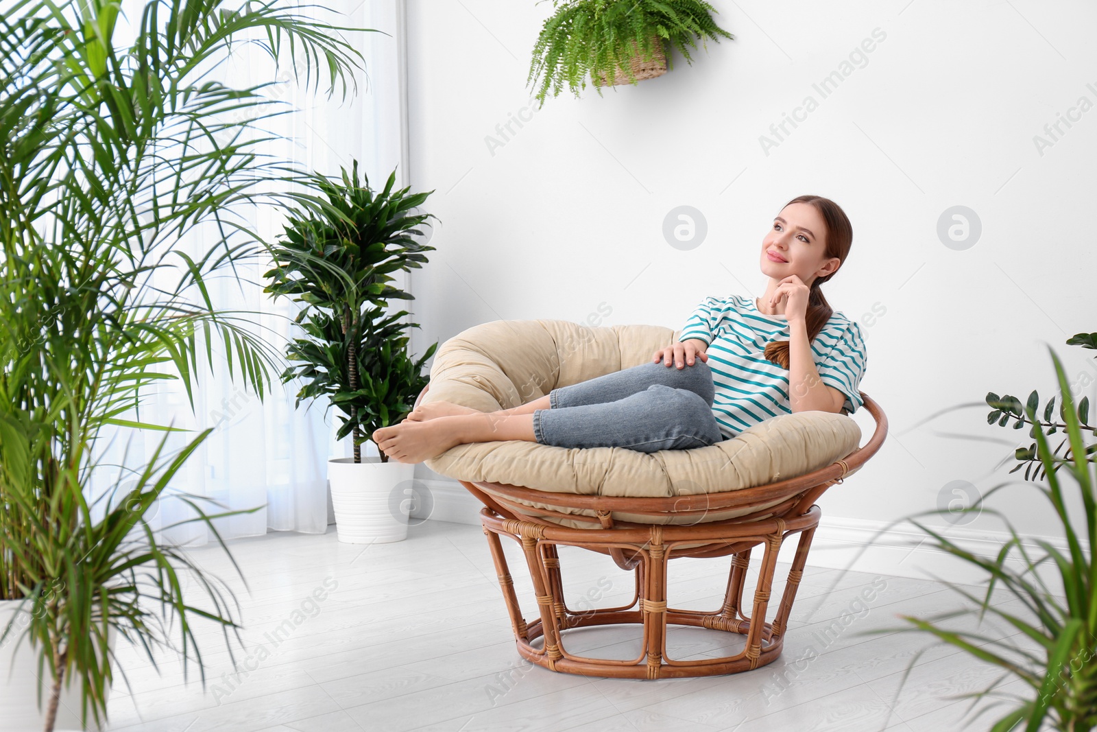 Photo of Young woman in room decorated with plants. Home design