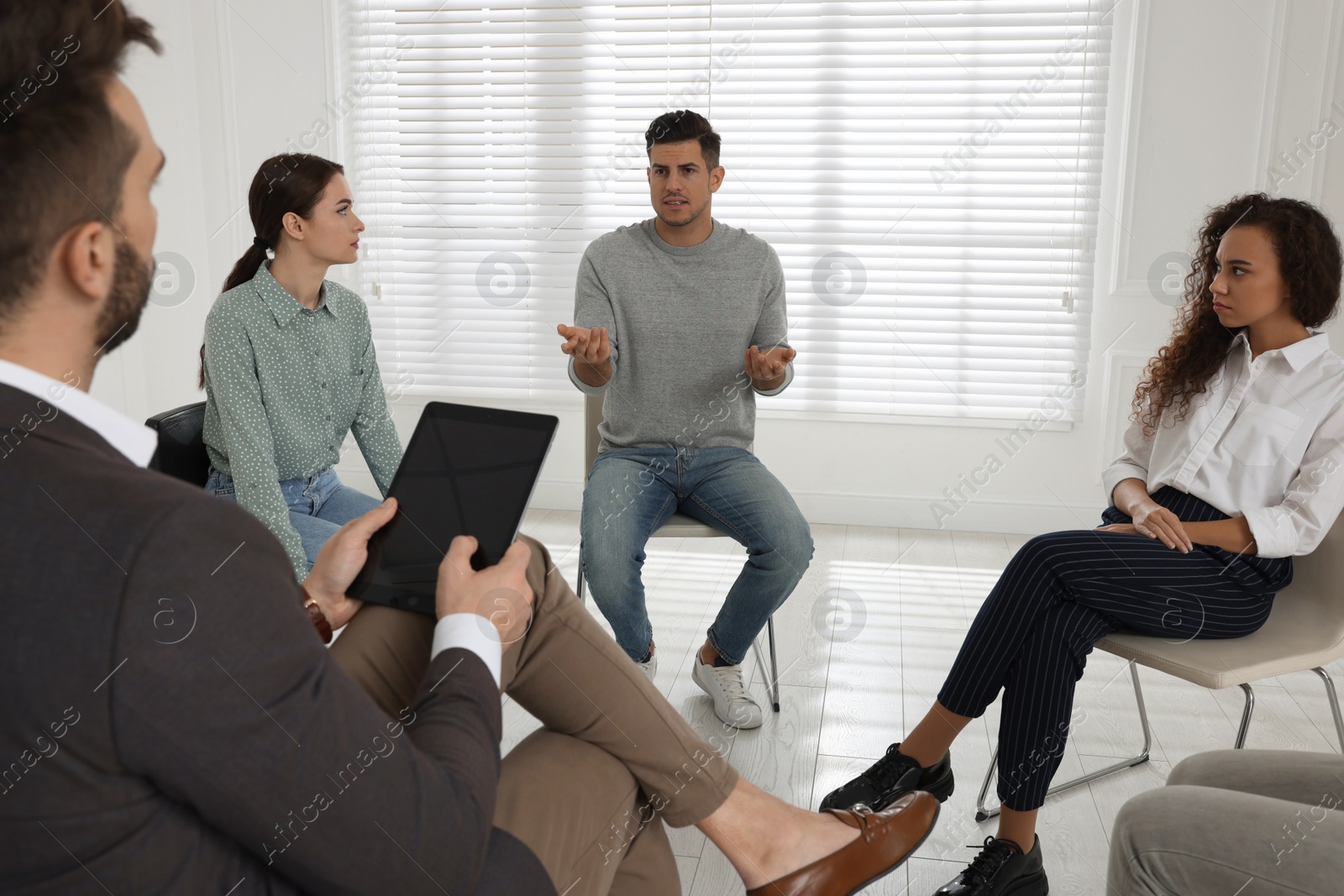 Photo of Psychotherapist working with patients at group session indoors