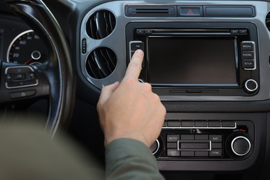 Photo of Choosing favorite radio. Man pressing button on vehicle audio in car, closeup