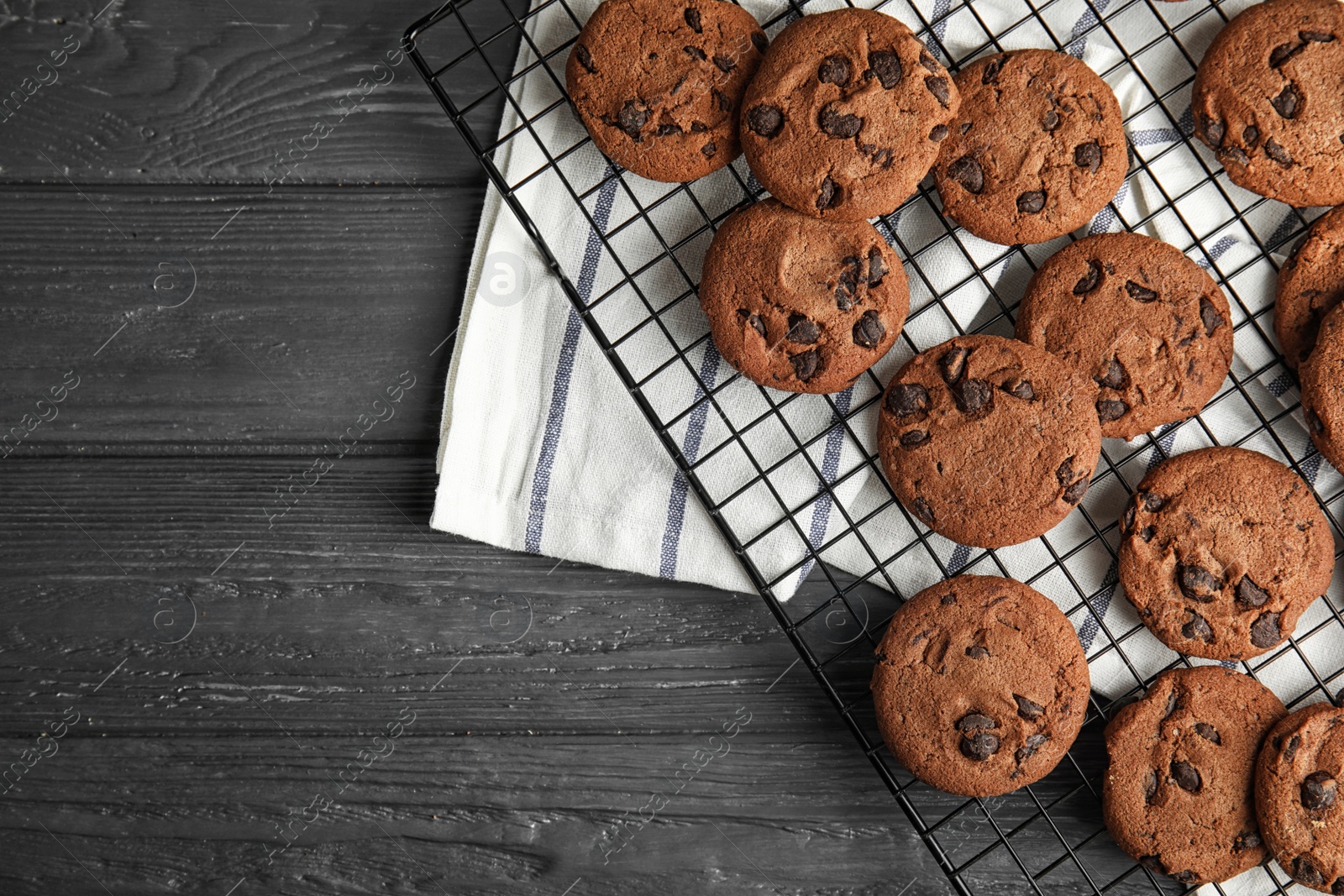 Photo of Cooling rack with chocolate chip cookies on wooden background, top view. Space for text