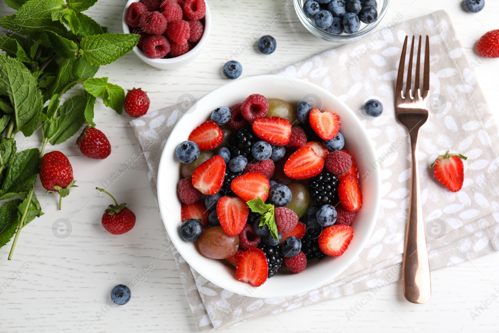 Photo of Fresh tasty fruit salad on white wooden table, flat lay