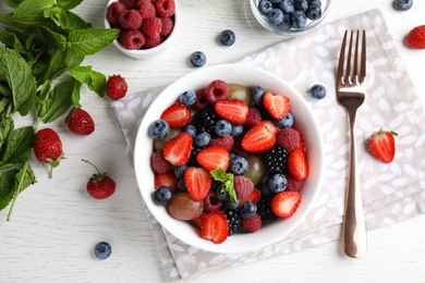 Fresh tasty fruit salad on white wooden table, flat lay