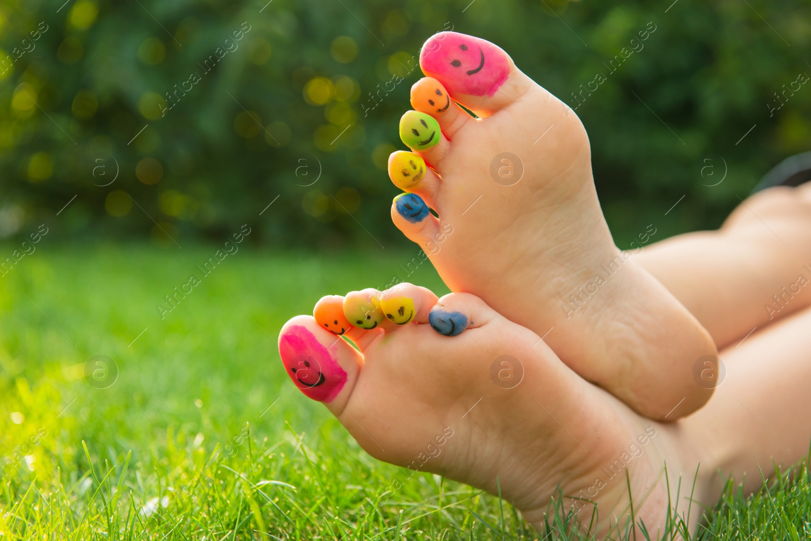 Photo of Teenage girl with smiling faces drawn on toes outdoors, closeup. Space for text