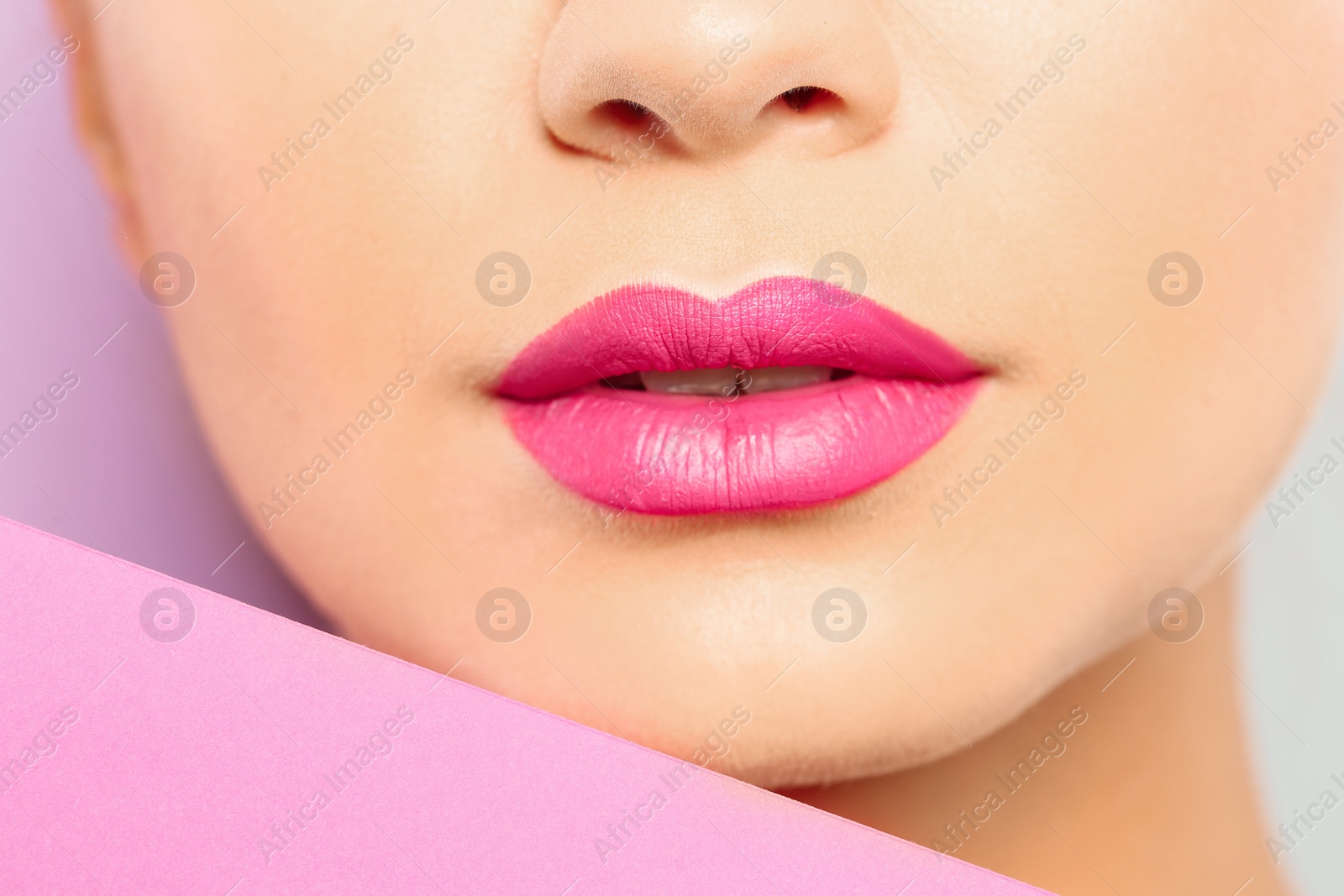 Photo of Young woman wearing beautiful lipstick on color background, closeup