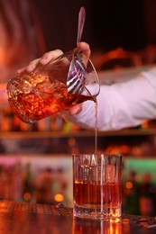 Photo of Bartender making fresh alcoholic cocktail at counter in bar, closeup