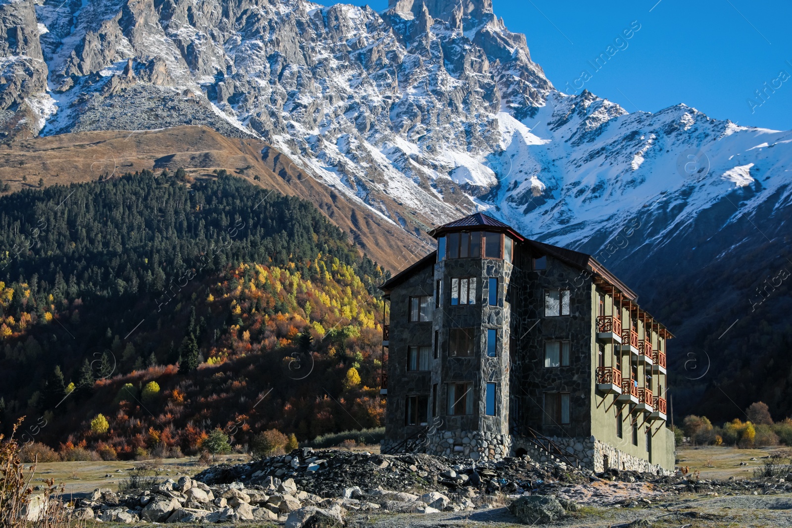 Photo of Picturesque view of high mountains and stone building on sunny day