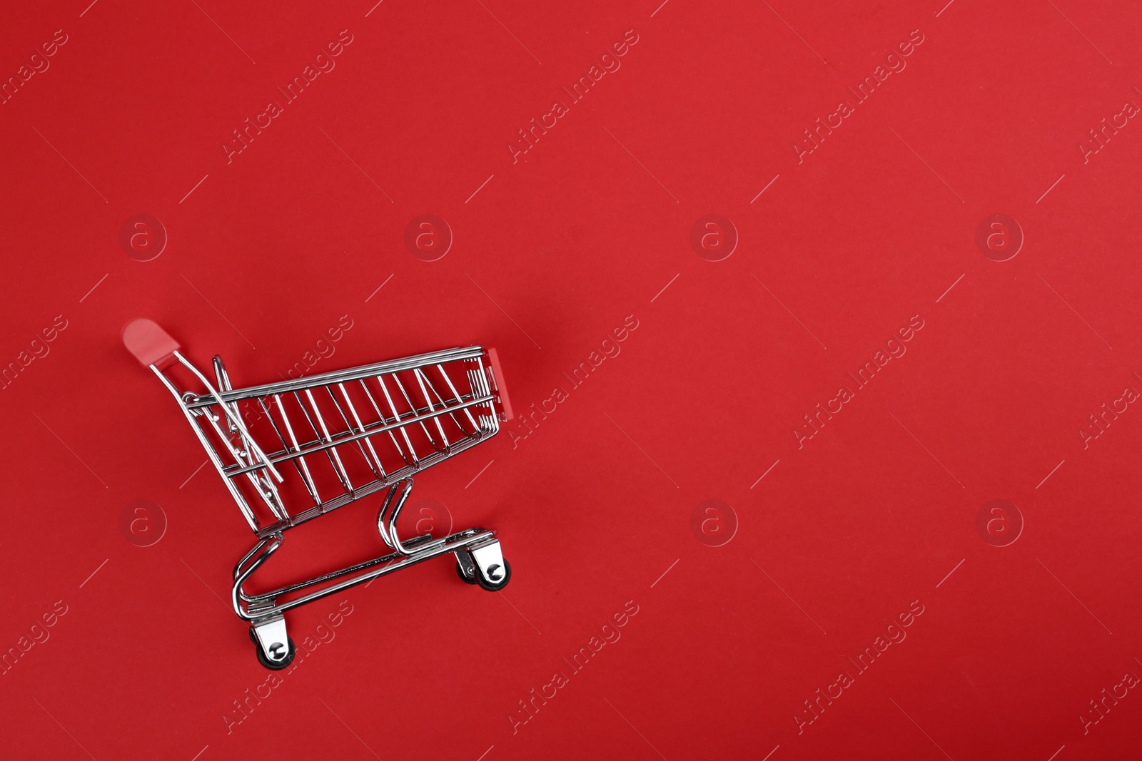 Photo of Empty shopping trolley on color background, top view. Space for text