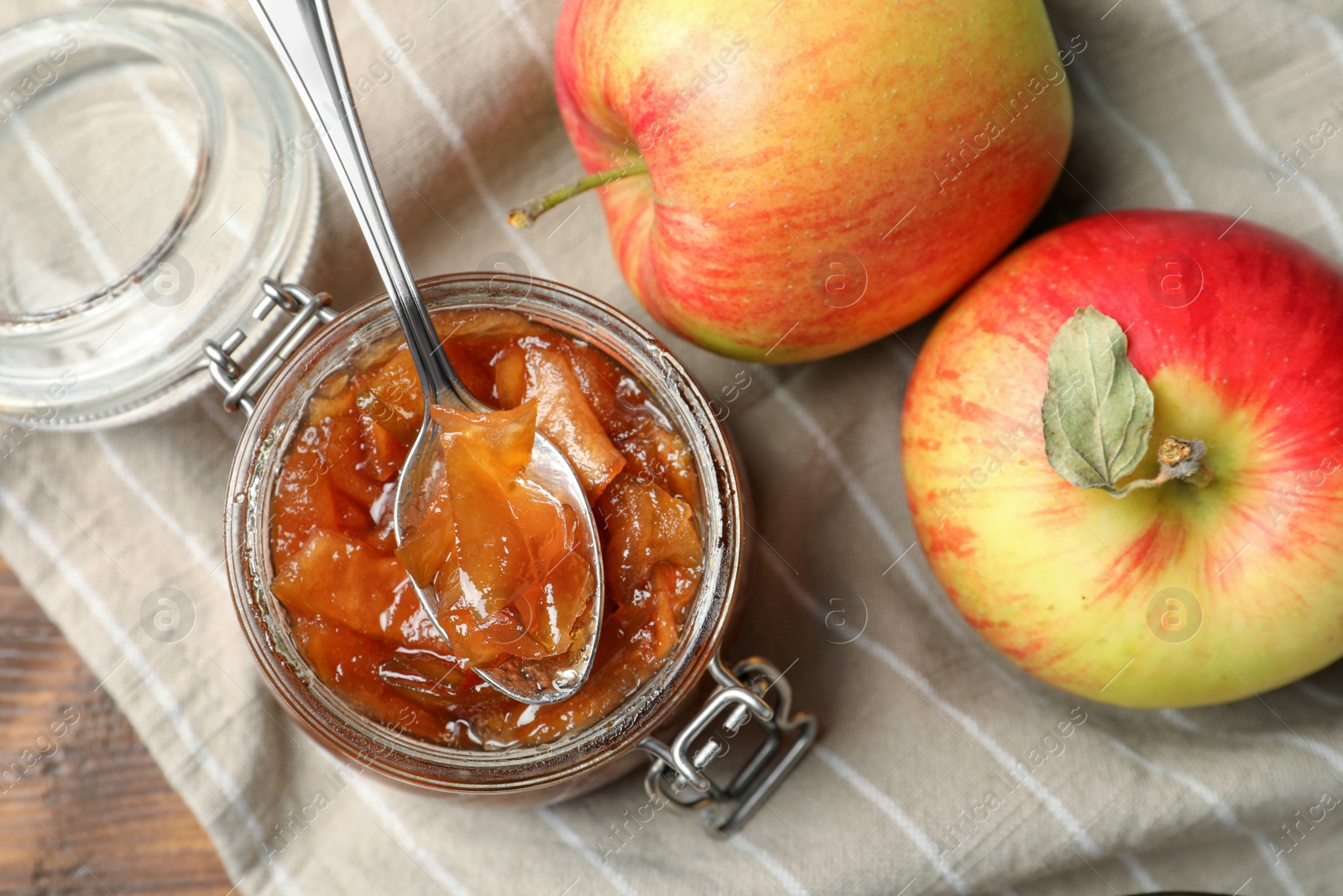 Photo of Tasty apple jam in glass jar and fresh fruits on wooden table, flat lay