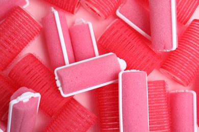 Photo of Different hair curlers on pink background, closeup. Styling tool