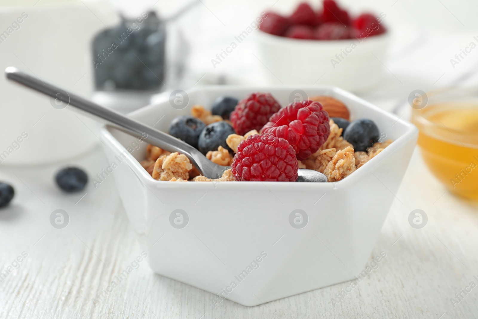 Photo of Healthy breakfast with granola and berries on white wooden table, closeup