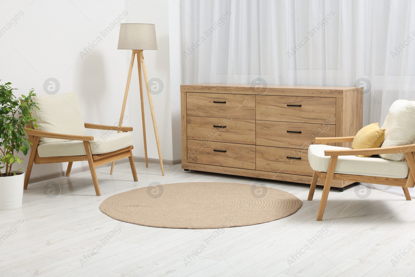 Photo of Stylish living room with chest of drawers, armchairs and lamp. Interior design