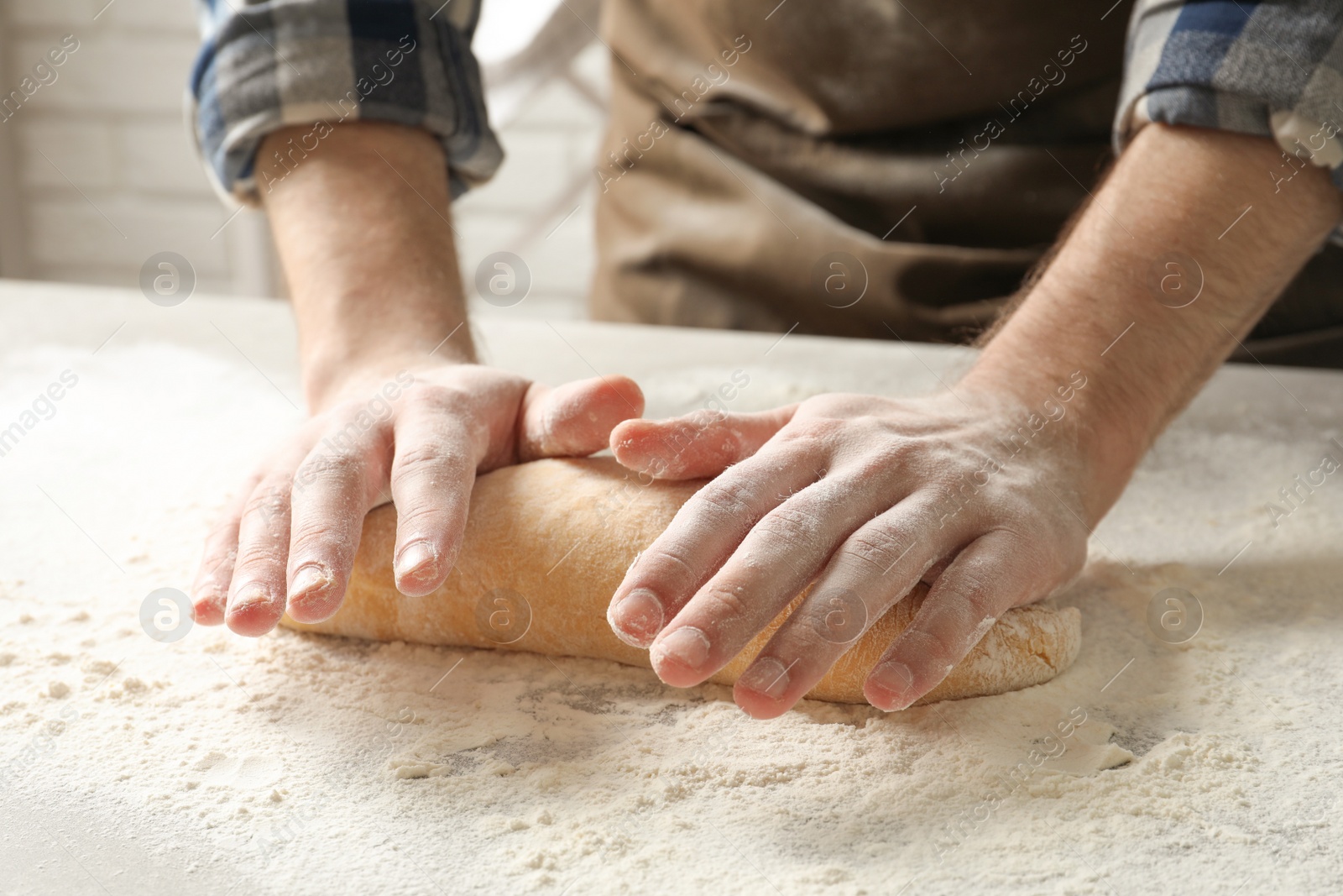 Photo of Young man kneading dough for pasta on table