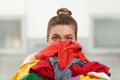 Photo of Woman holding pile of dirty laundry indoors