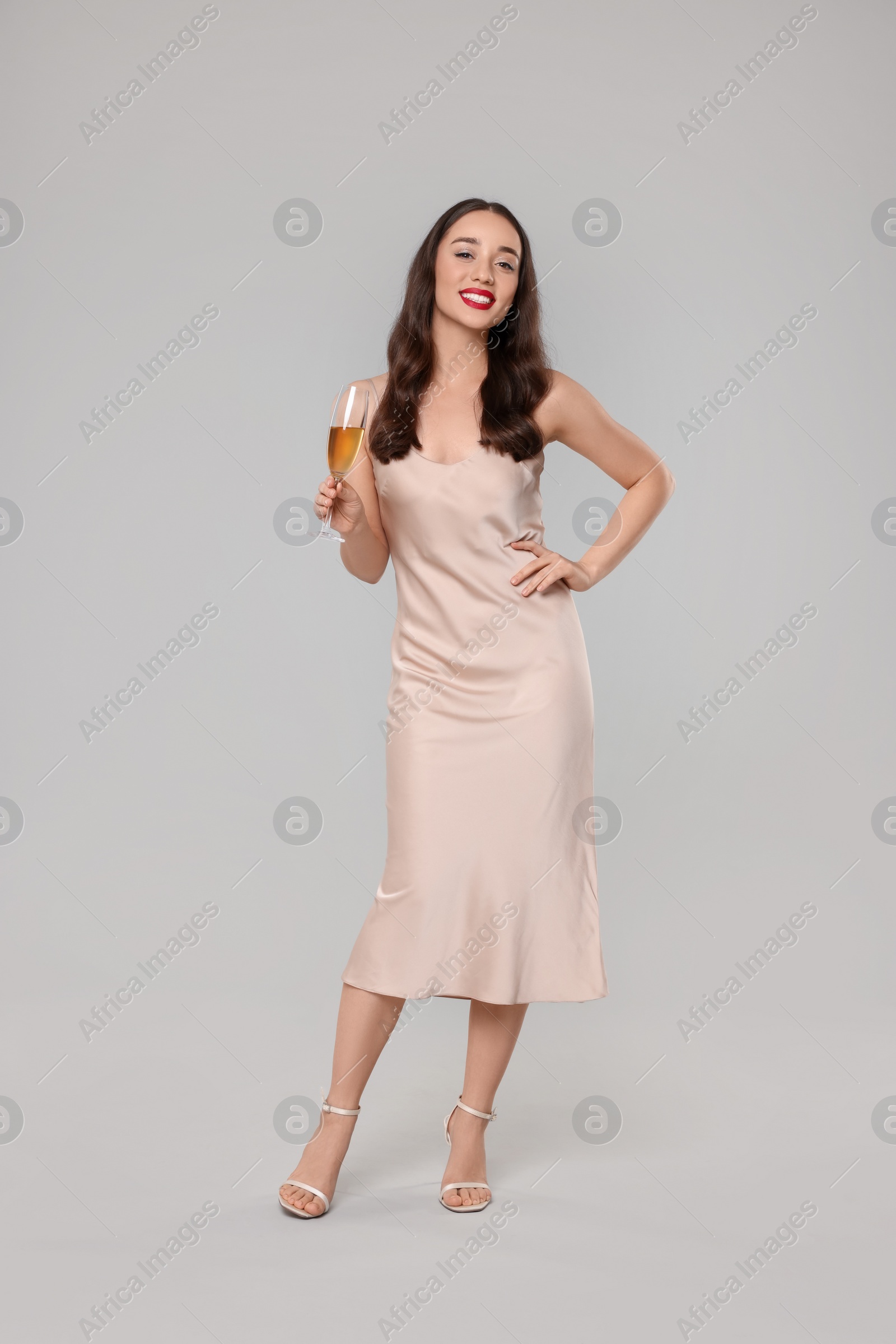 Photo of Christmas celebration. Beautiful young woman with glass of champagne on grey background
