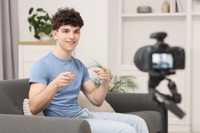 Photo of Smiling teenage blogger explaining something while streaming at home