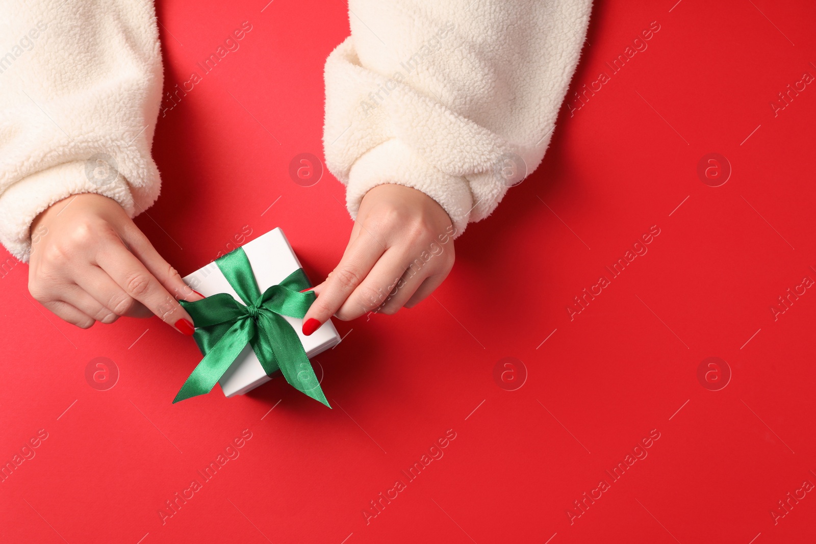 Photo of Christmas present. Woman with gift box on red background, top view. Space for text