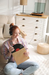 Young woman listening to music with turntable in living room