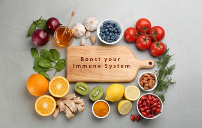 Photo of Set of natural products and wooden board with text Boost Your Immune System on grey table, flat lay