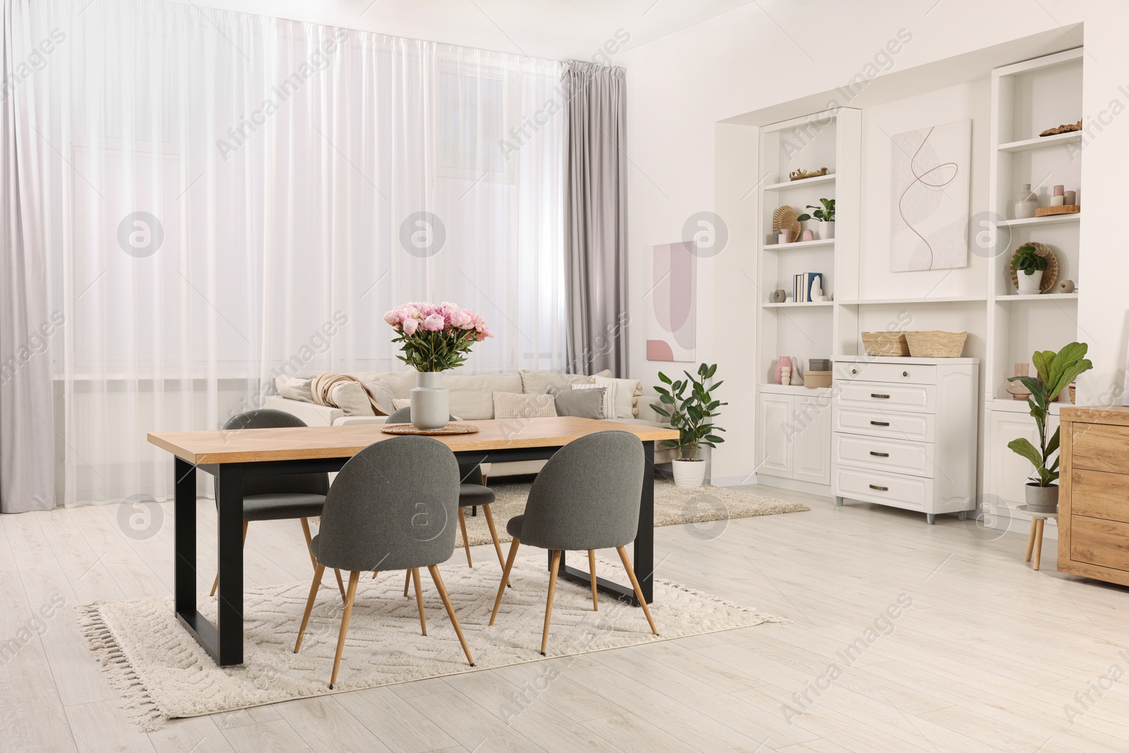 Photo of Stylish dining room with cosy furniture and flowers