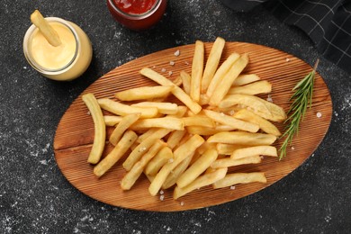 Delicious french fries served with sauces on grey textured table, flat lay