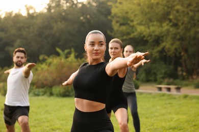Photo of Group of people practicing yoga in park outdoors, selective focus