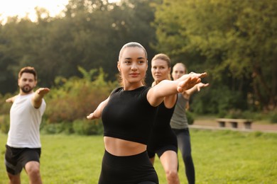 Group of people practicing yoga in park outdoors, selective focus