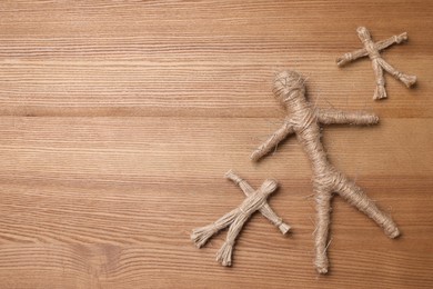 Photo of Voodoo dolls with pins on wooden table, flat lay. Space for text