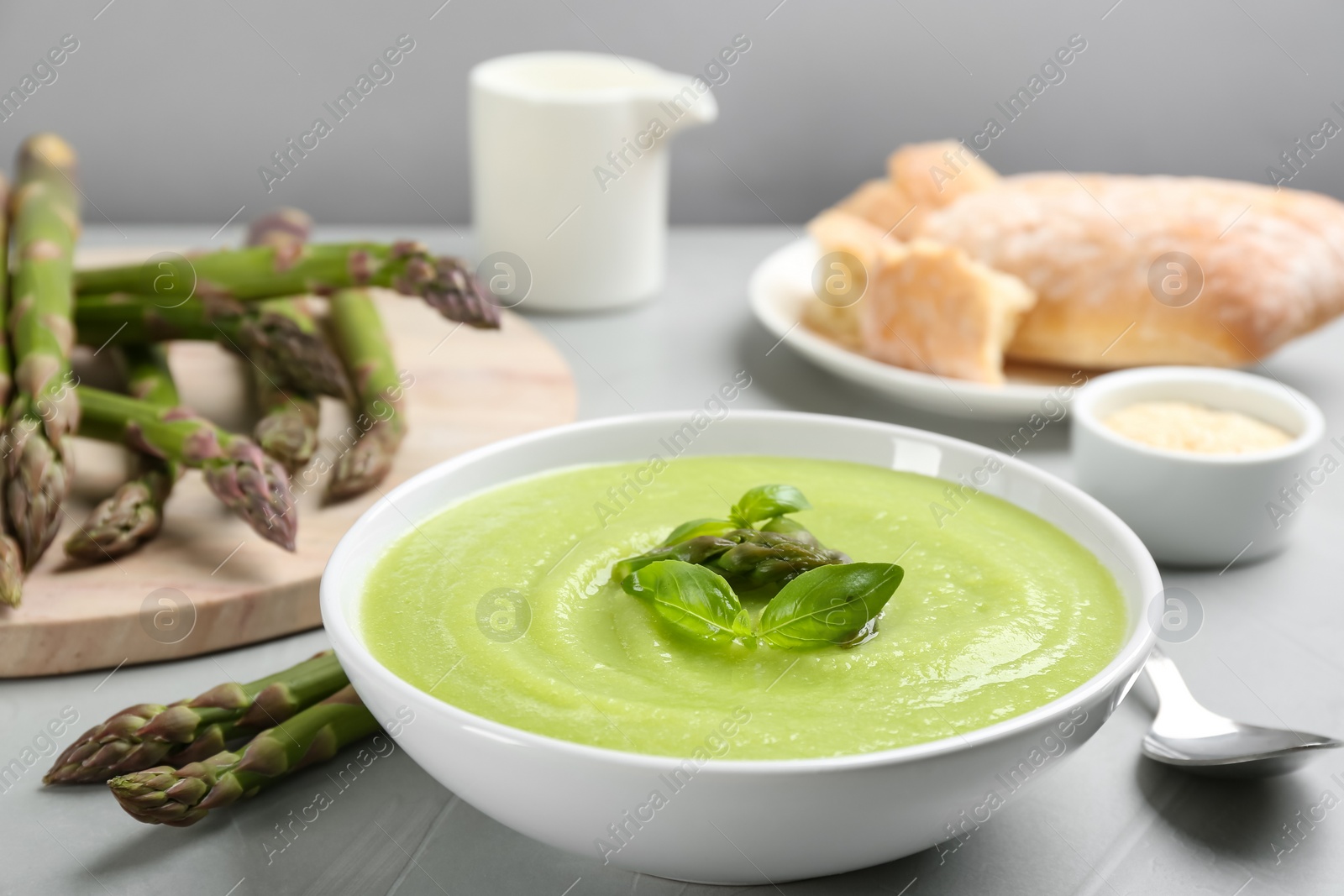 Photo of Delicious asparagus soup served on grey table