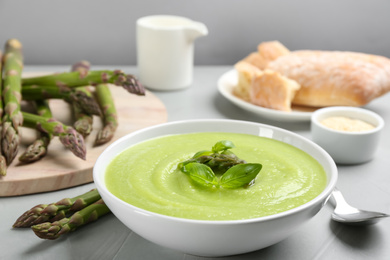 Delicious asparagus soup served on grey table