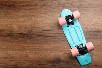 Photo of Turquoise skateboard on wooden background, top view. Space for text