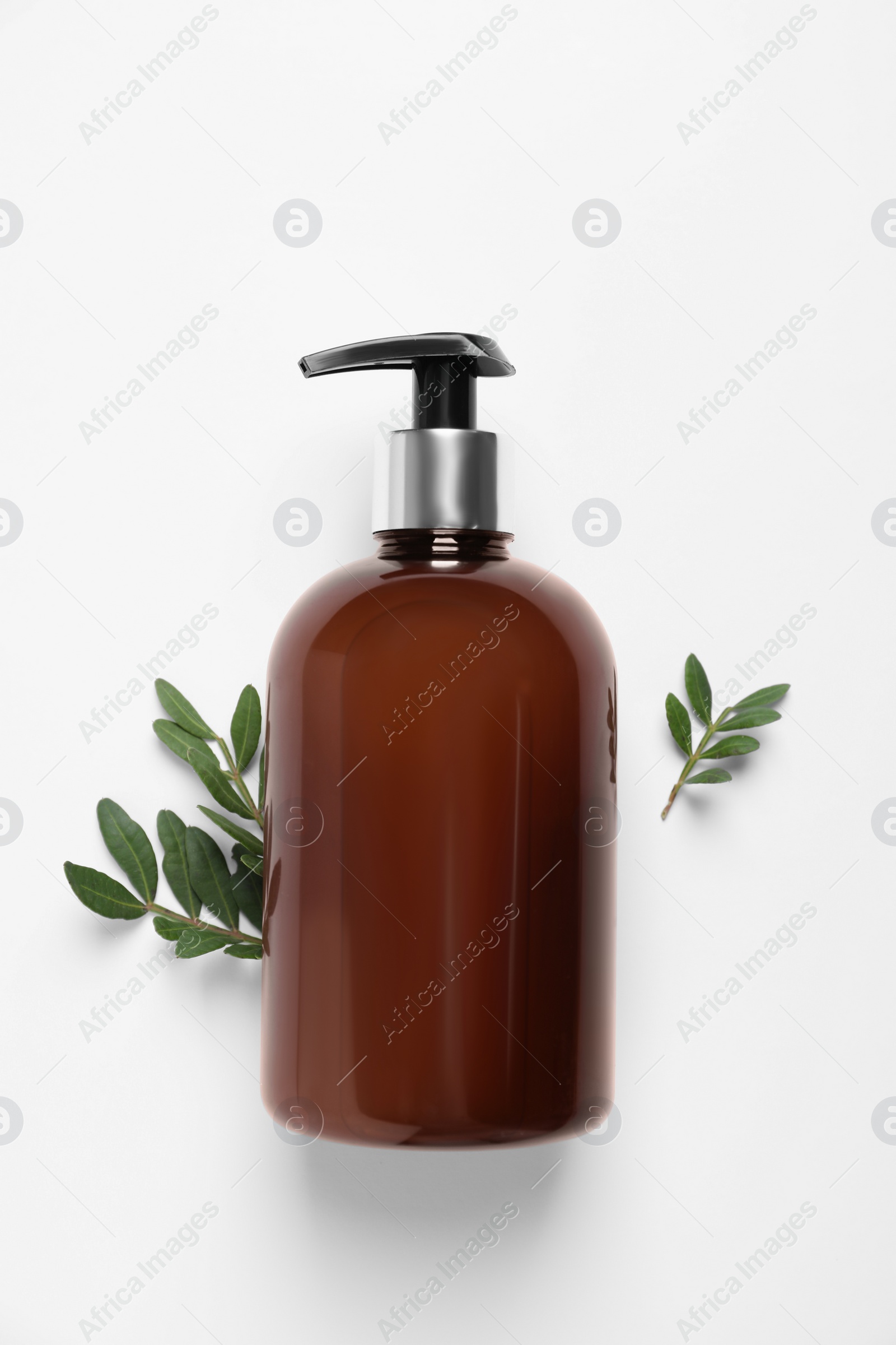 Photo of Bottle of cosmetic product and green leaves on white background, flat lay