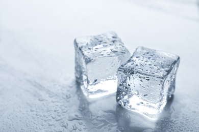 Photo of Crystal clear ice cubes with water drops on light table, closeup