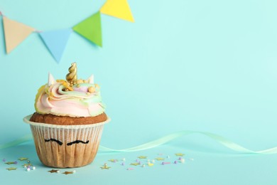 Photo of Cute sweet unicorn cupcake on light turquoise background, space for text