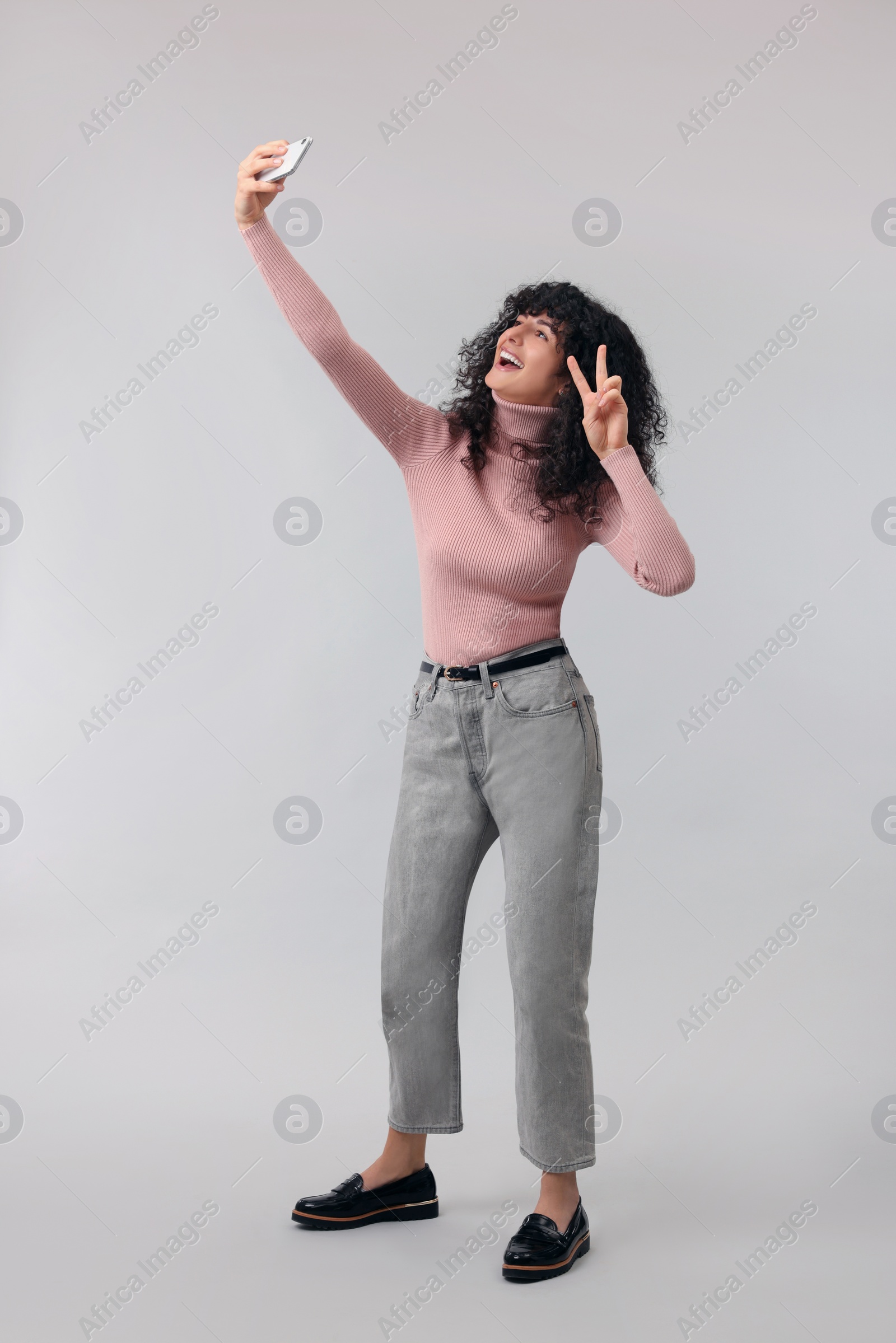 Photo of Beautiful young woman taking selfie on light grey background