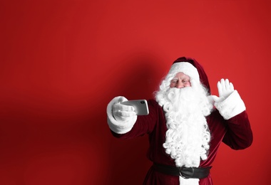 Photo of Authentic Santa Claus taking selfie on red background. Space for text
