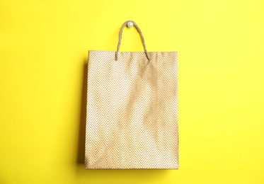 Photo of Gold shopping paper bag on yellow background