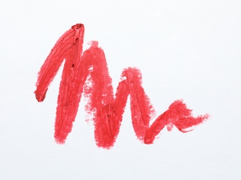 Photo of Red lipstick smear on white background, top view