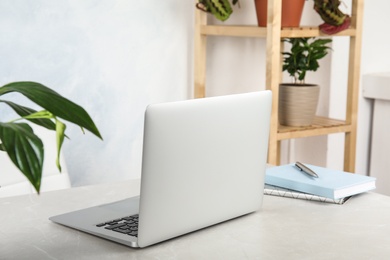 Office interior with houseplants and laptop on table