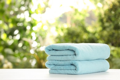 Stack of clean soft towels on table against blurred background. Space for text